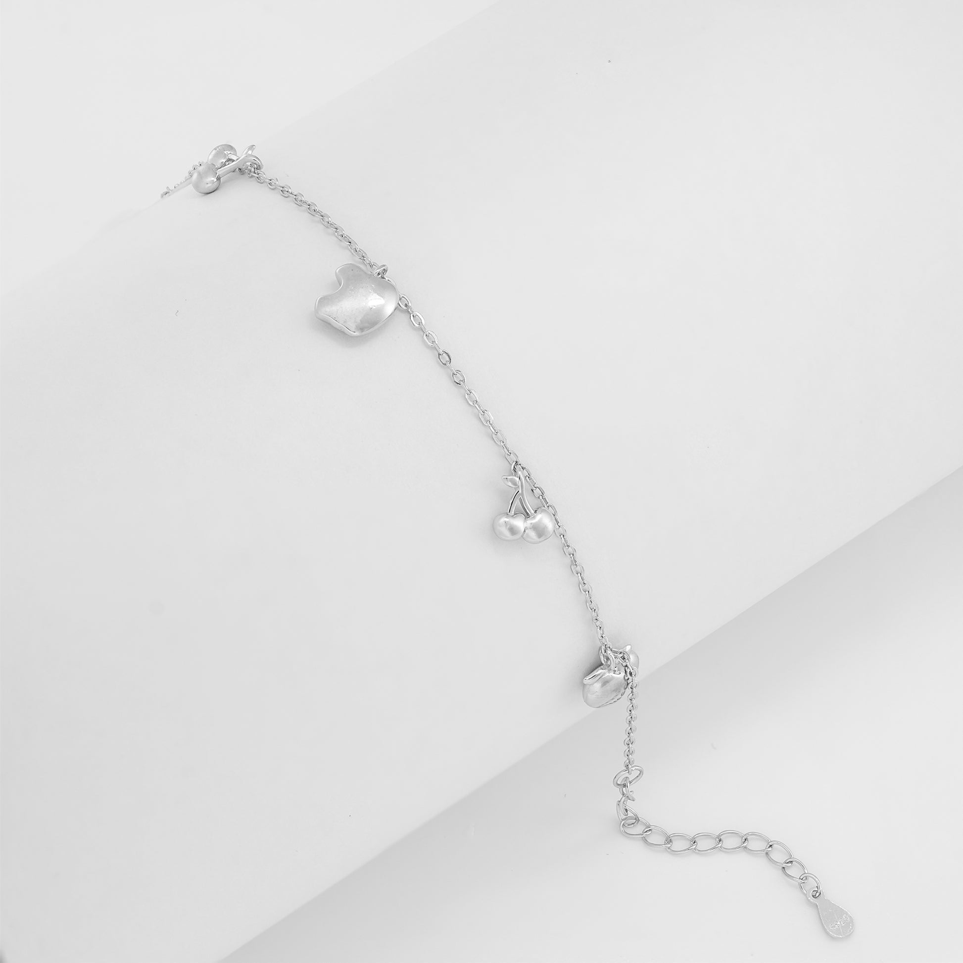 Close-up of the Apple-Cherry charm bracelet crafted in 925 sterling silver featuring apple, cherry, and playful fruit charms on a delicate silver-toned chain.