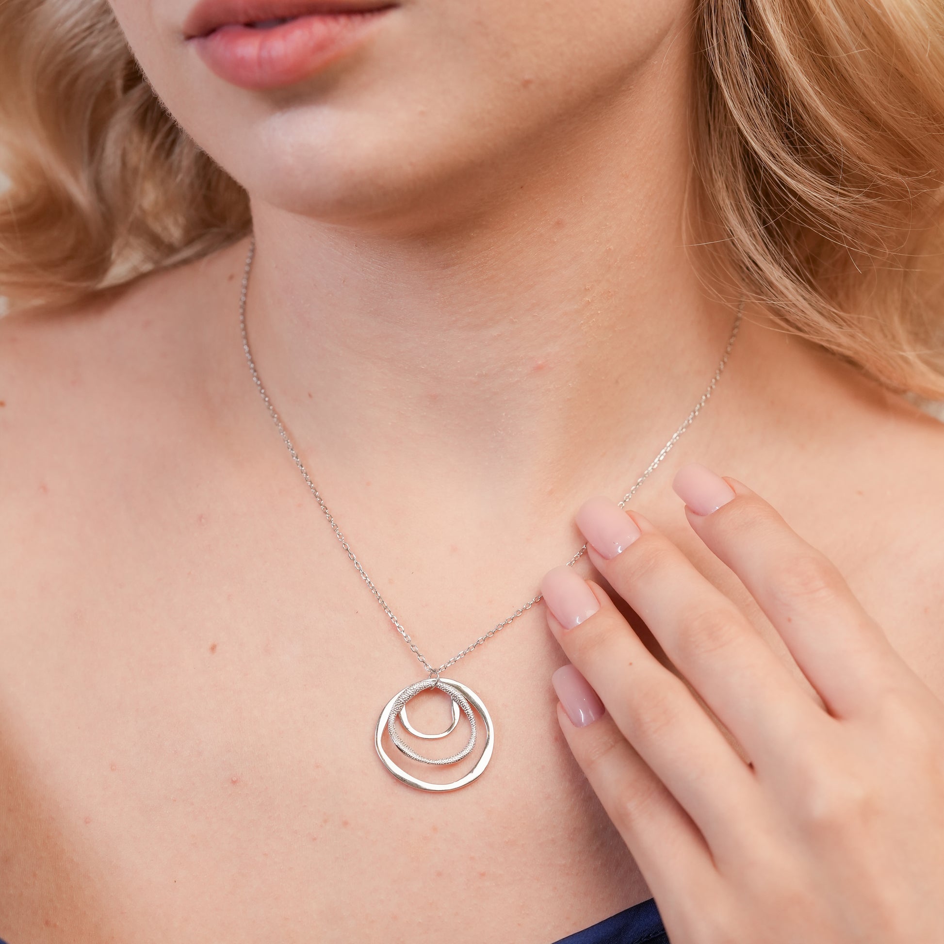 Model wearing the Infinity Ripple Pendant Necklace in 925 sterling silver, showcasing its minimalist triple‑ring design paired with a casual chic outfit.