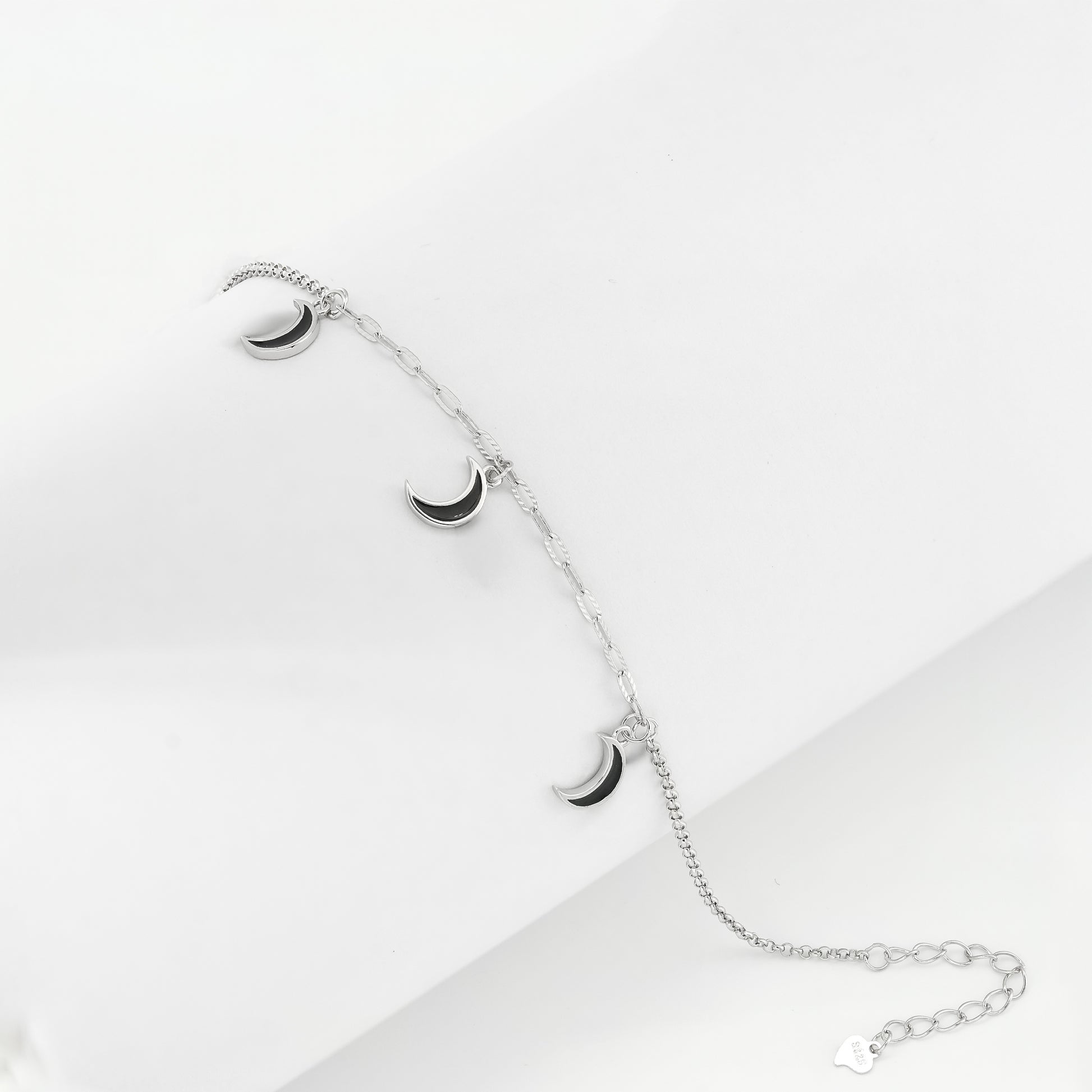 Silver-toned bracelet with three crescent moon charms on a plain background.
