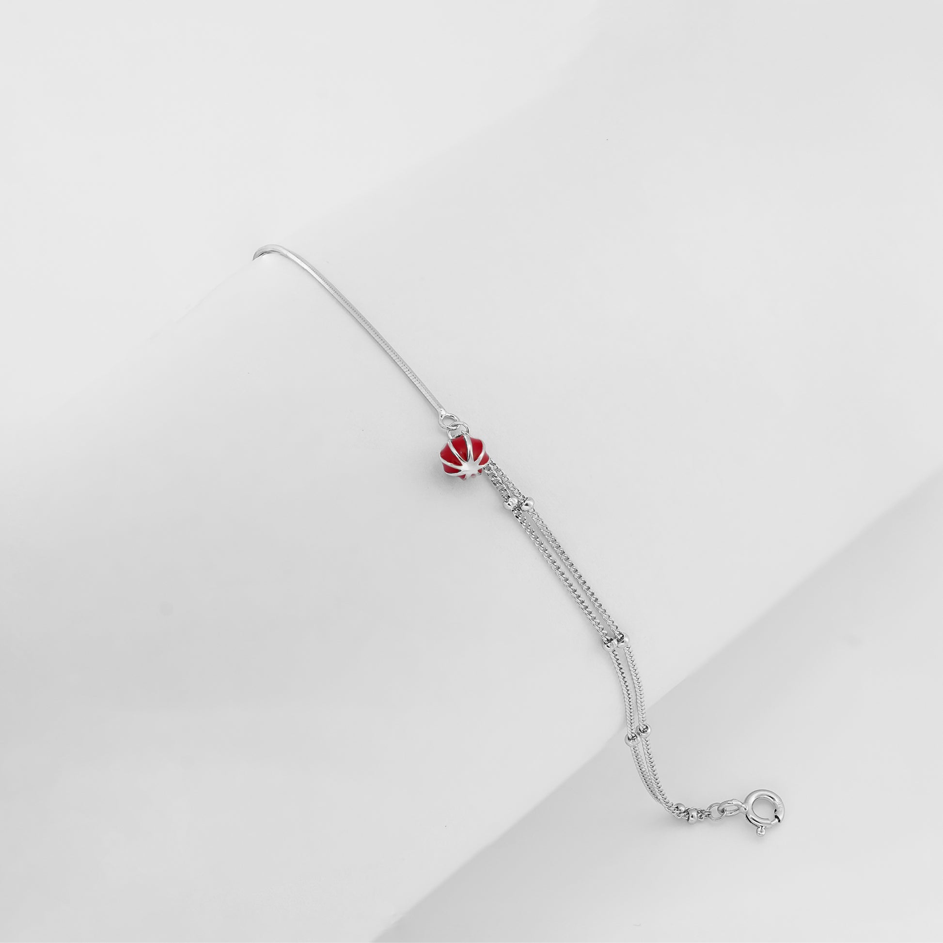 Minimal silver bracelet with a bold red charm and dual-strand chain, displayed on a white background.