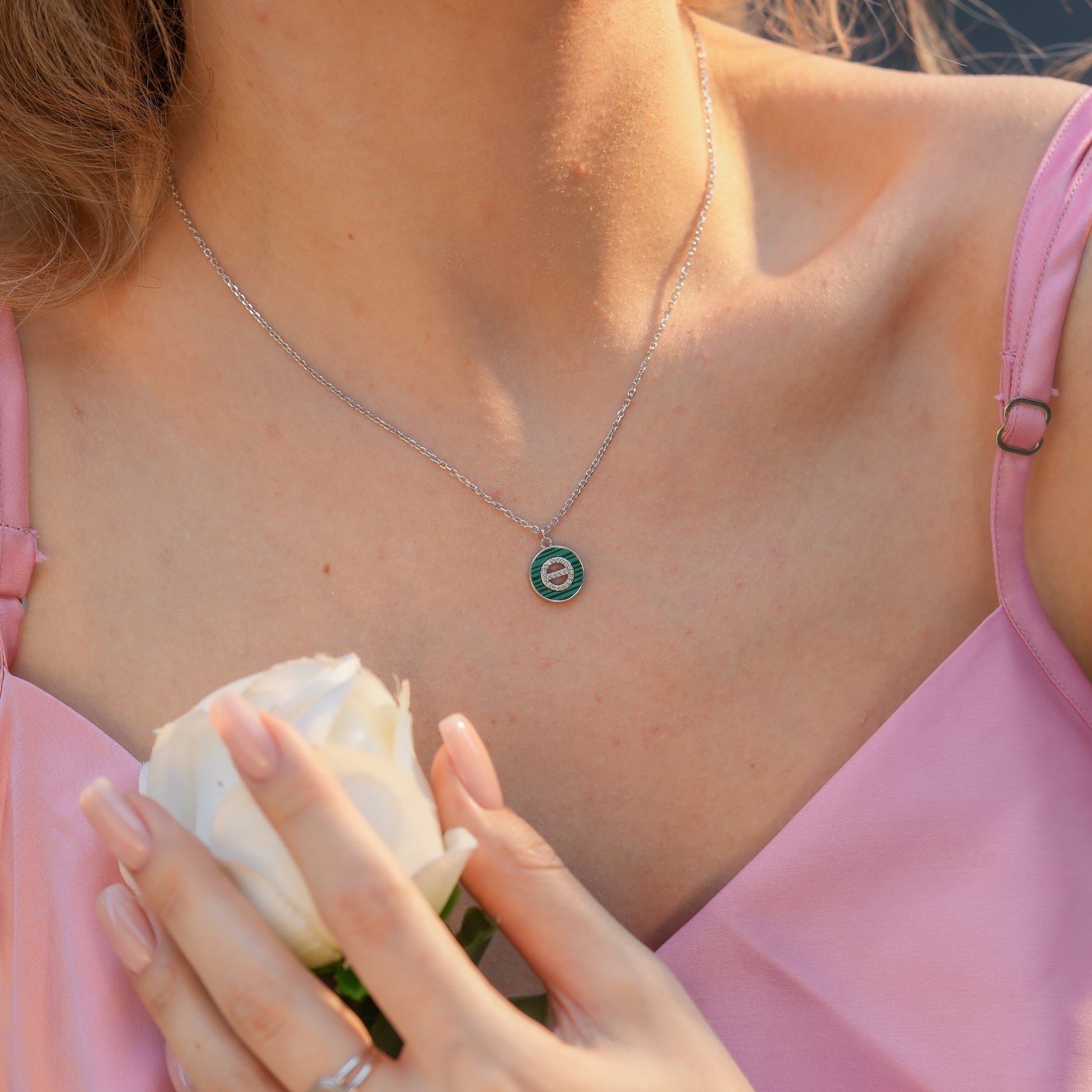 Model wearing the Malachite Orbit Pendant Necklace showcasing a polished silver medallion with green malachite and a sparkling CZ centerpiece.