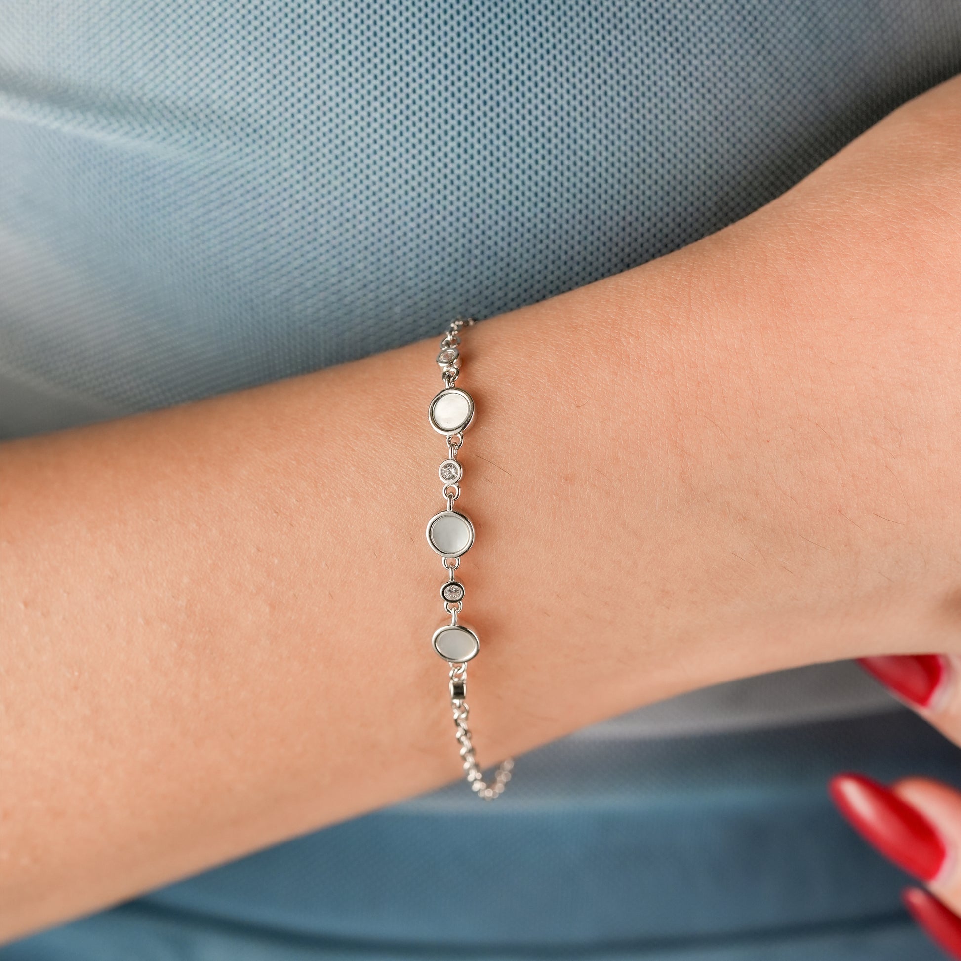 Elegant woman wearing sterling silver moonbeam bracelet styled with a pastel outfit