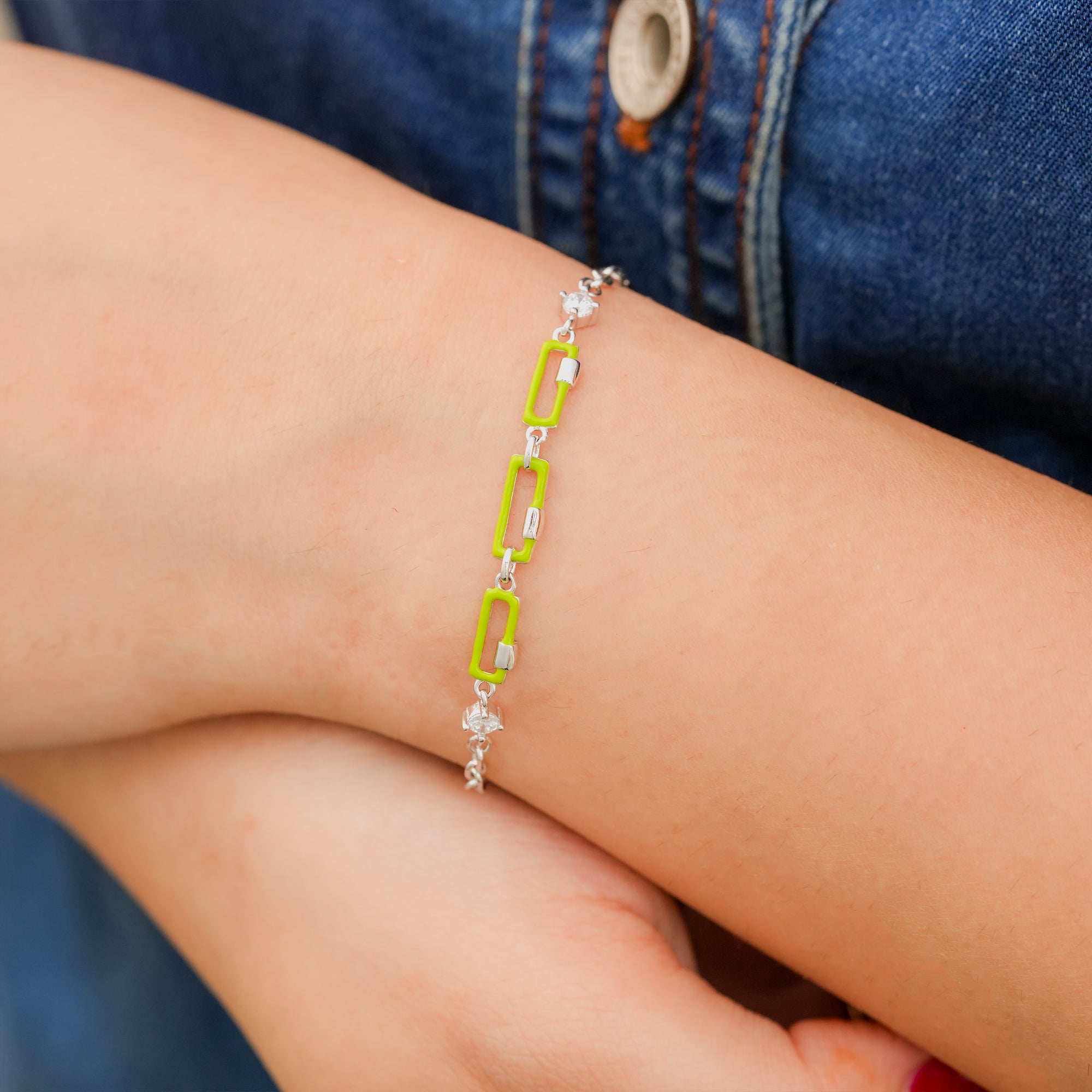 Model wearing a bold neon lime and silver link bracelet styled with casual denim.