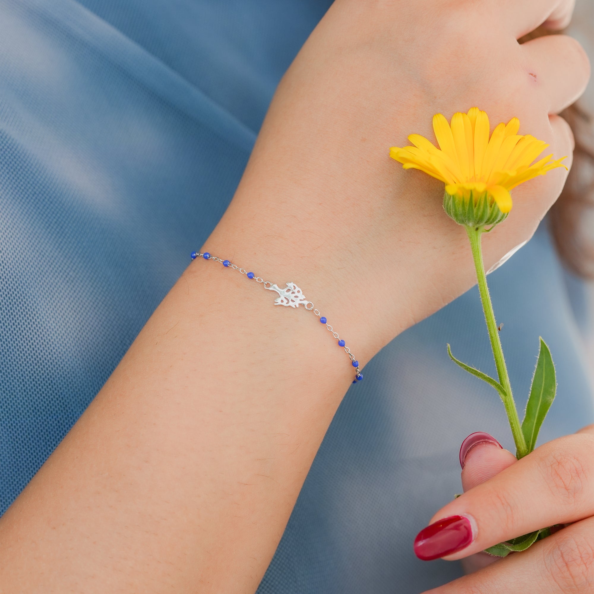 Model wearing a silver and blue bead bracelet styled with minimal accessories.