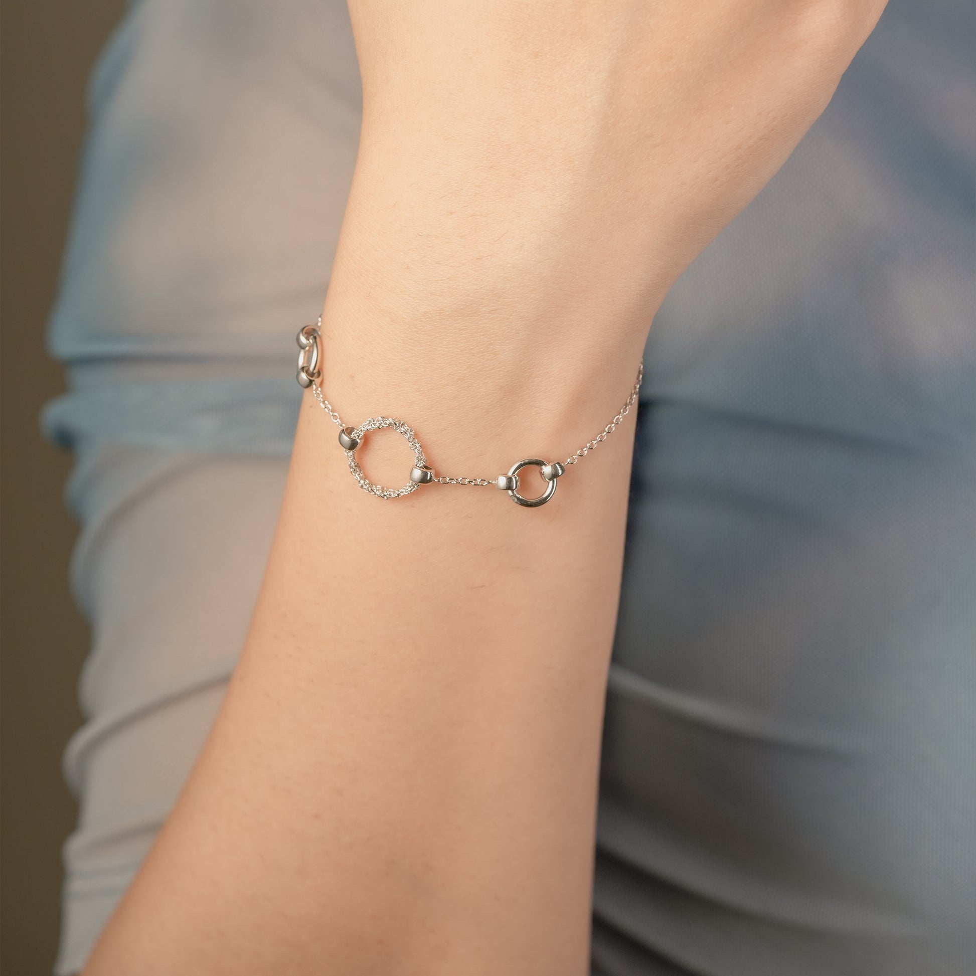 Minimalist bracelet with CZ charm styled on a woman’s wrist, paired with neutral-toned outfit.