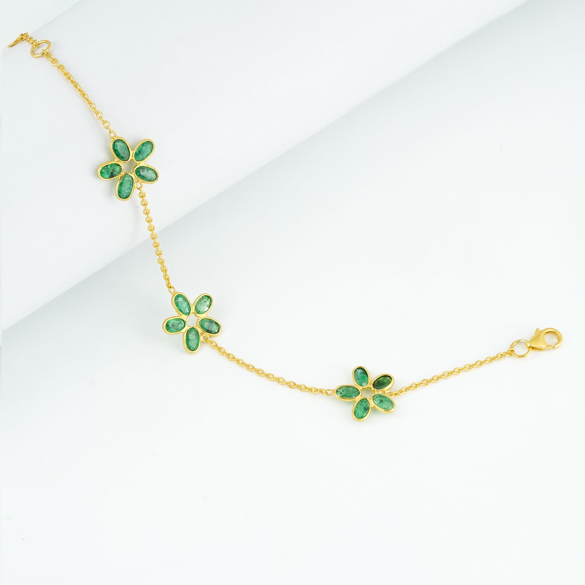 "Botanical Gardens Triple-Flower Emerald Bracelet in 925 sterling silver with gold plating, featuring 15 natural bluish-green emeralds in 3 floral clusters."