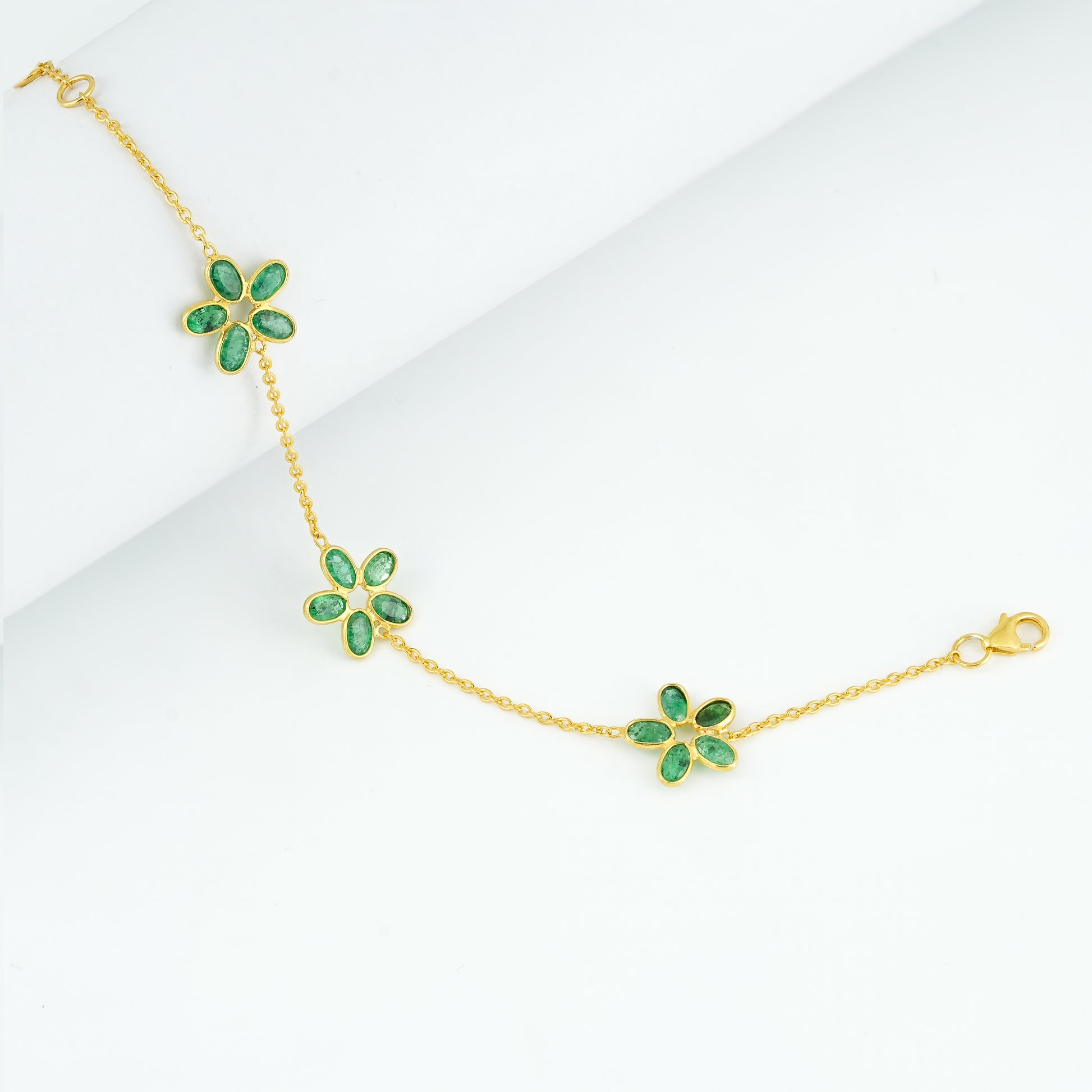 "Botanical Gardens Triple-Flower Emerald Bracelet in 925 sterling silver with gold plating, featuring 15 natural bluish-green emeralds in 3 floral clusters."