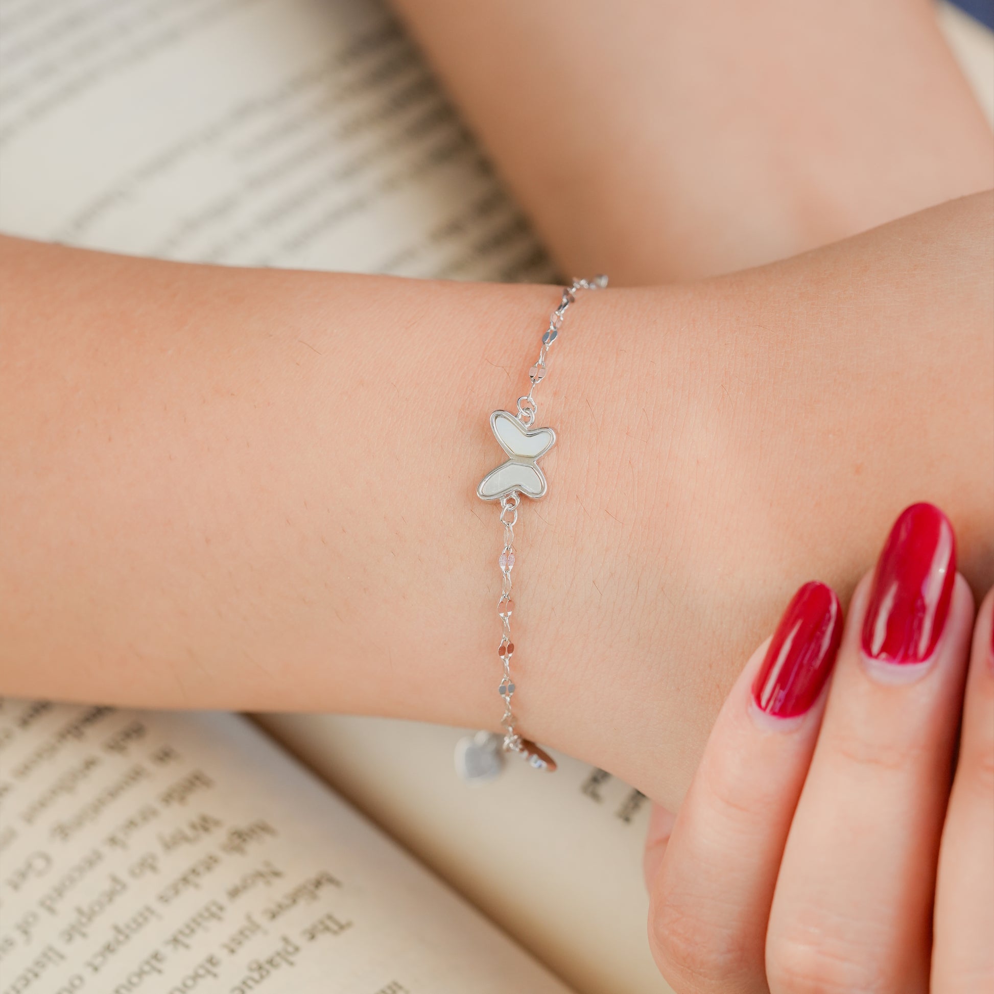 Model wearing Luna Bloom butterfly bracelet styled with pastel clothing