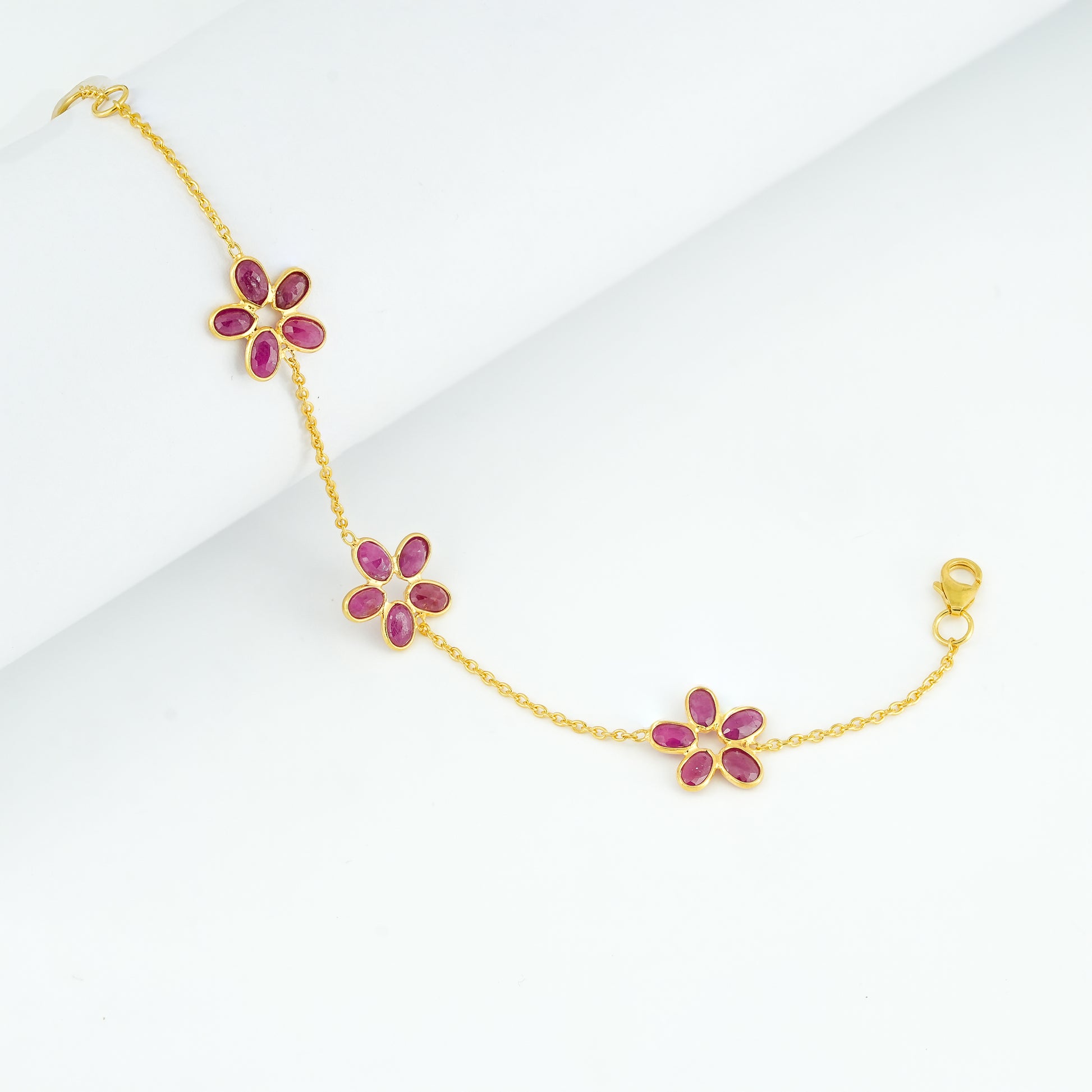 "Rose Gardens Triple-Flower Ruby Bracelet in 925 sterling silver with gold plating, featuring 15 natural purplish-red rubies in 3 floral clusters."