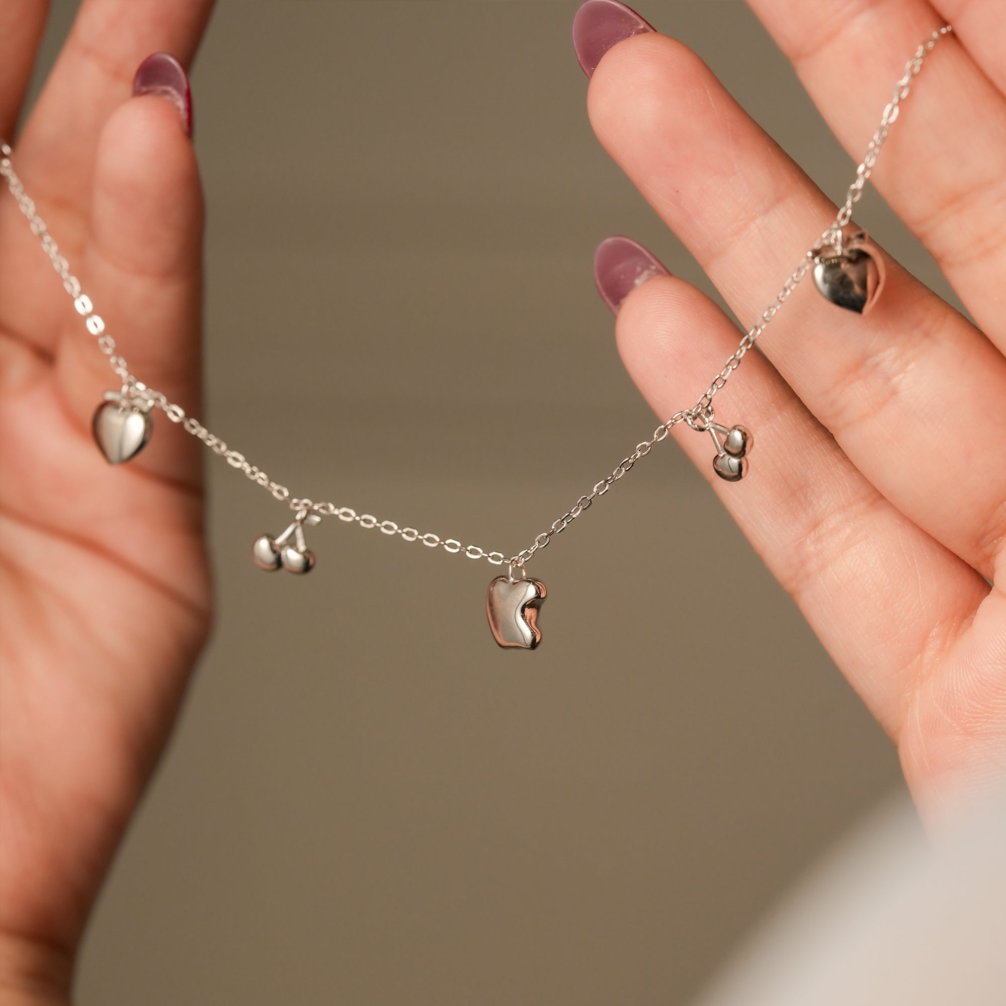Close-up of the Apple-Cherry charm bracelet crafted in 925 sterling silver featuring apple, cherry, and playful fruit charms on a delicate silver-toned chain.