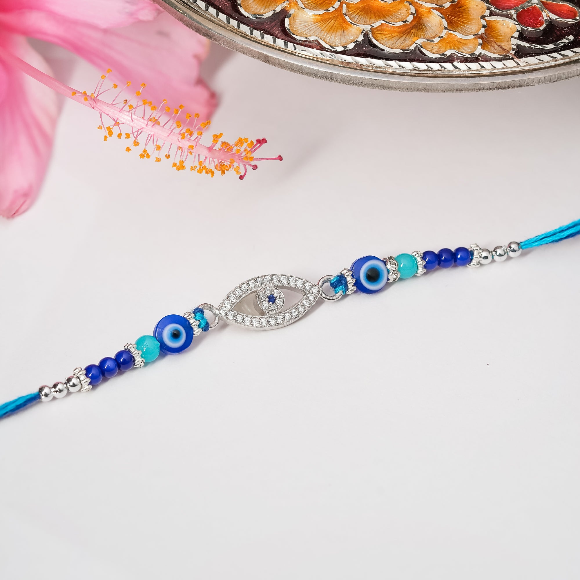 925 silver rakhi with blue and white evil eye design on adjustable thread.