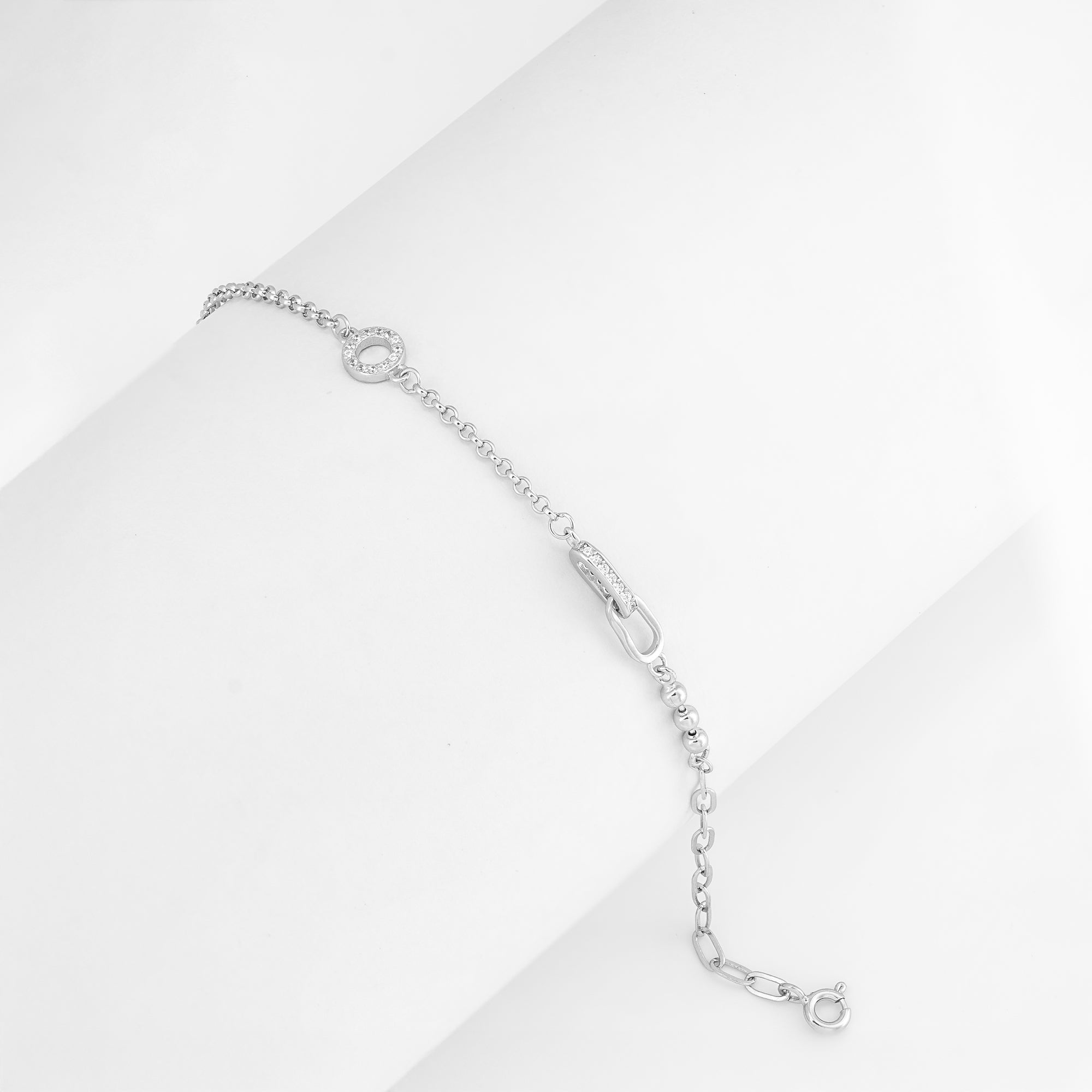 Delicate silver bracelet featuring a circular pavé charm, laid flat on a white background.

