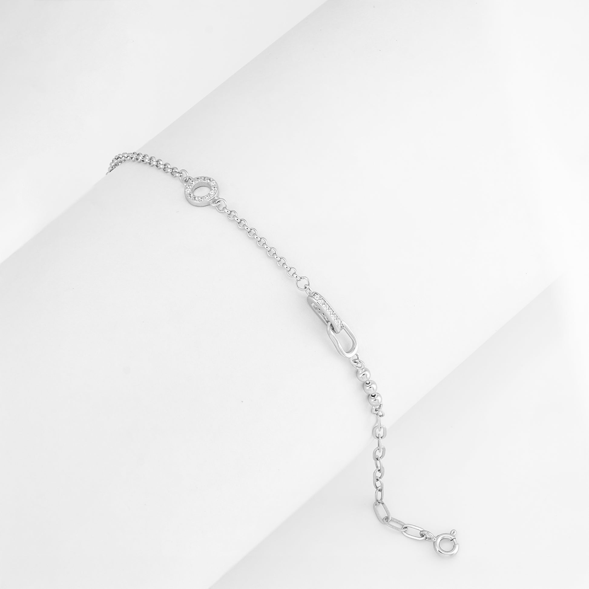 Delicate silver bracelet featuring a circular pavé charm, laid flat on a white background.

