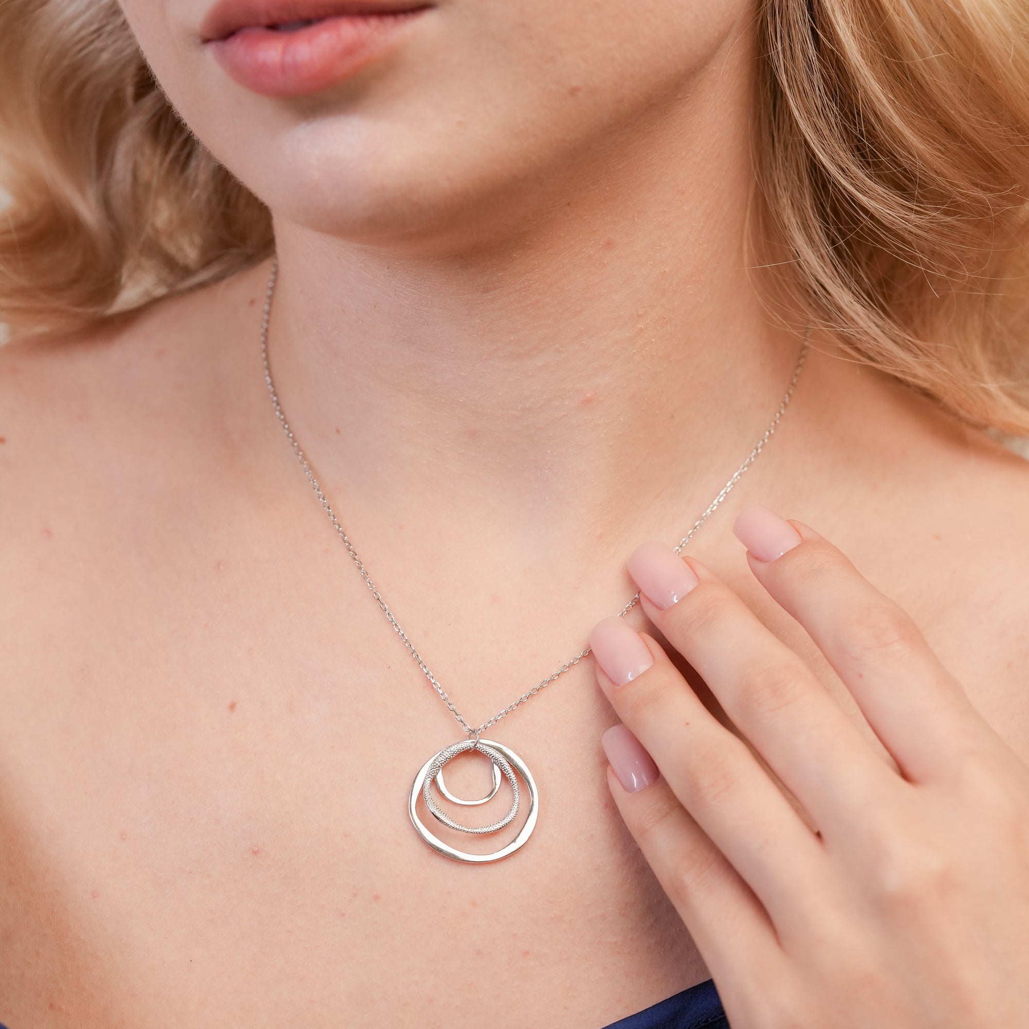  Model wearing the Infinity Ripple Pendant Necklace in 925 sterling silver, showcasing its minimalist triple‑ring design paired with a casual chic outfit.