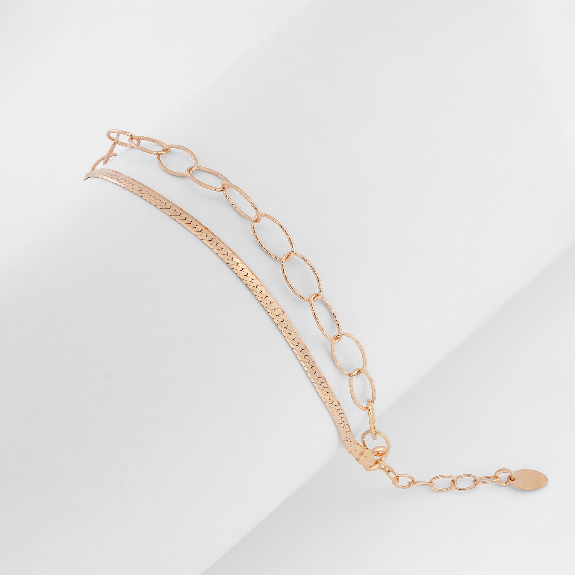 Rose gold bracelet featuring bold oval links and a sleek chain on a plain background.