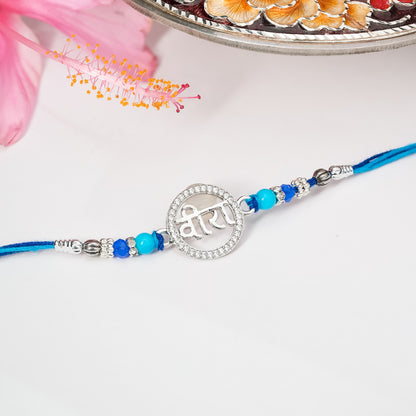 Rakhi in sterling silver with symbolic centerpiece tied on soft thread, displayed on plain background.

