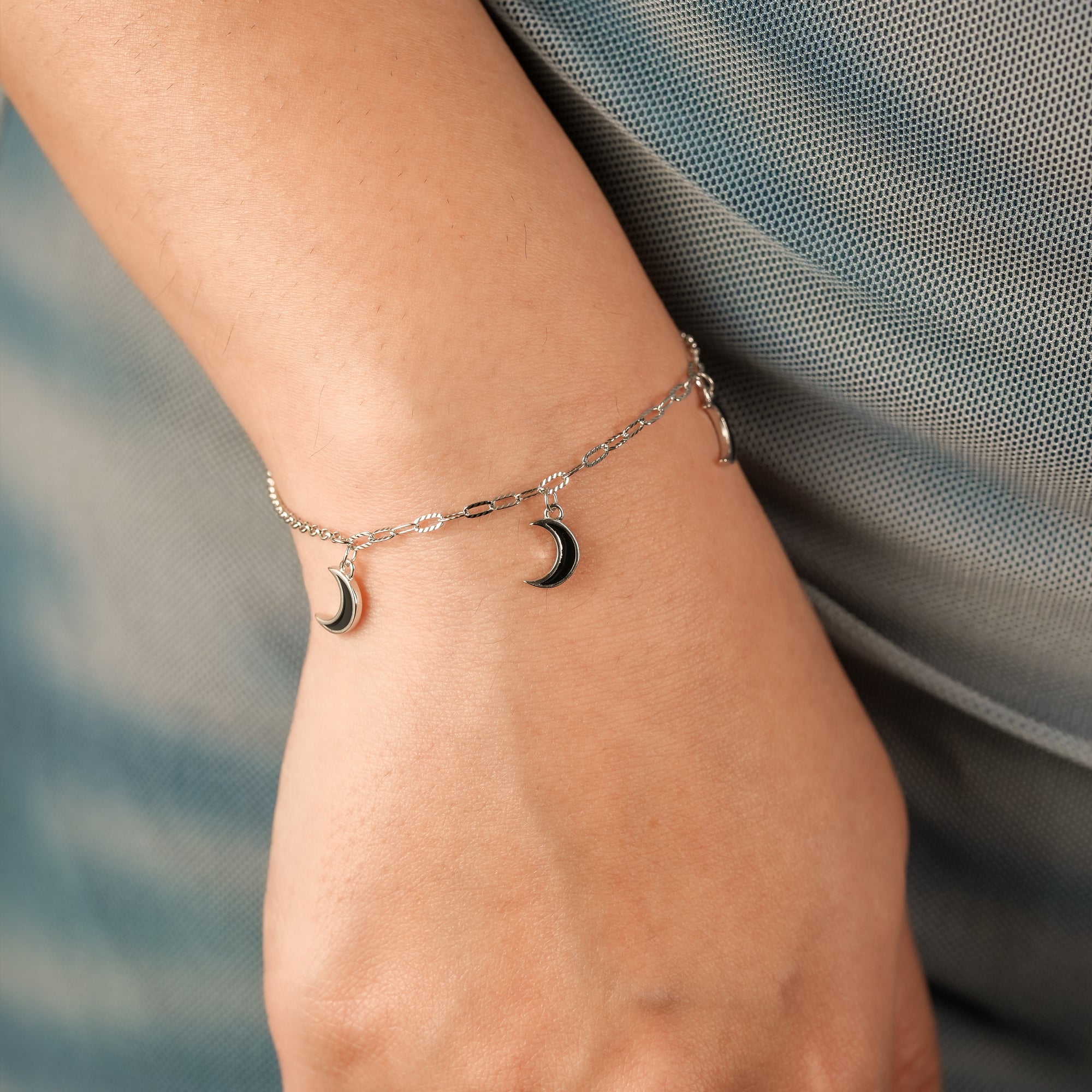 Delicate crescent moon bracelet on a model’s wrist, styled with a minimal, soft-toned outfit.