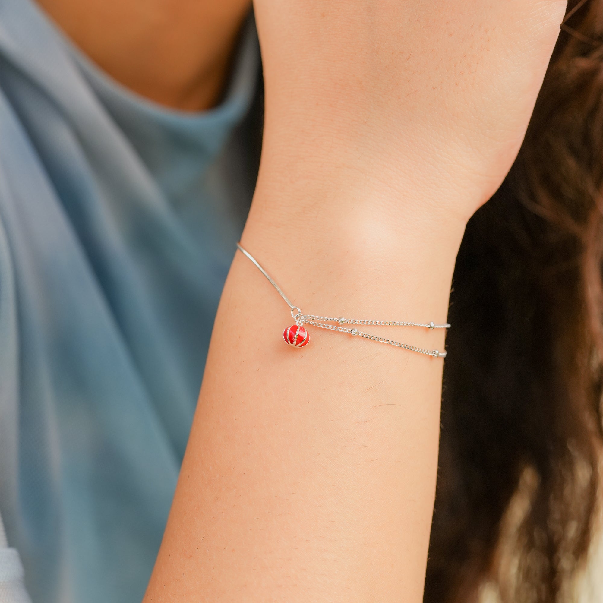 Model showcasing the Scarlet Drop Bracelet styled with a neutral outfit to highlight the red charm.