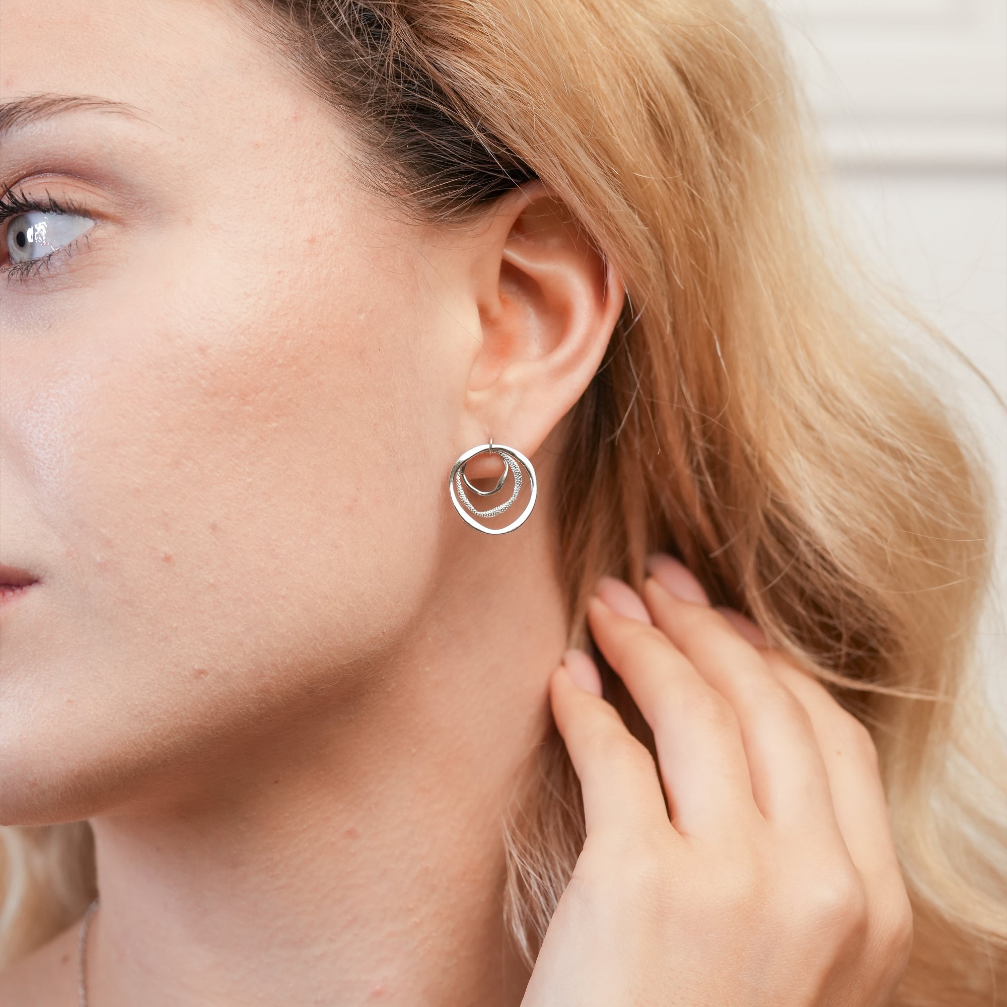  Modern concentric circle earrings styled on a woman with a sleek hairstyle and monochrome outfit.
